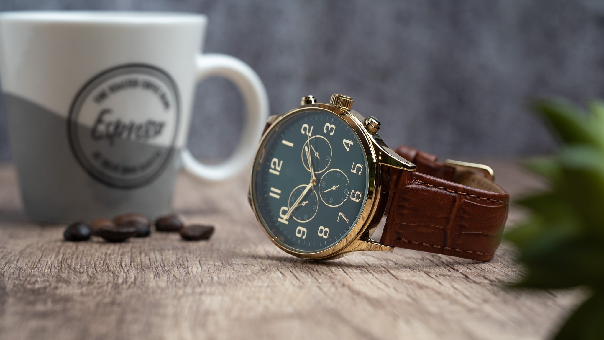 A lifestyle picture of a gold chronograph watch on a table with a brown leather crocodile watch strap.