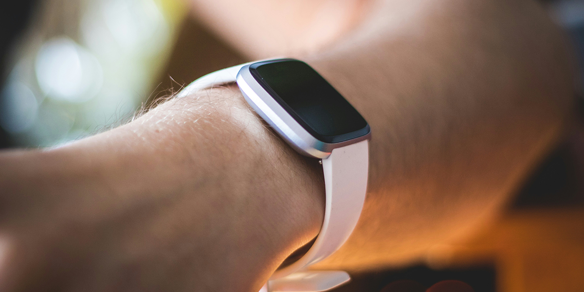 A lifestyle image of a person wearing a Fitbit watch with a replacement white strap.