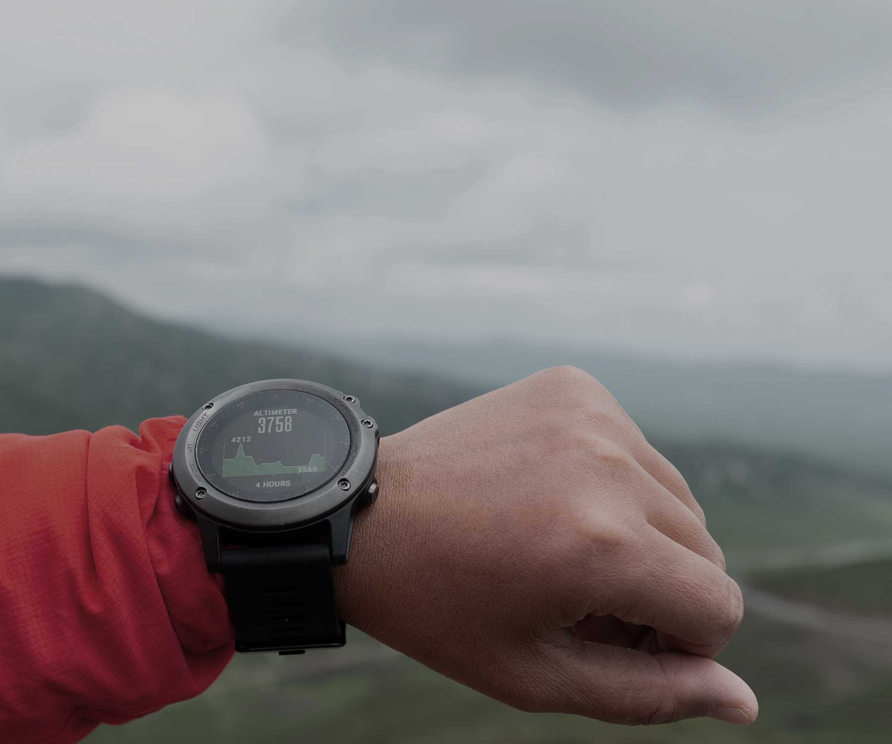 A lifestyle image of a person wearing a Garmin watch outdoors in the mountain.