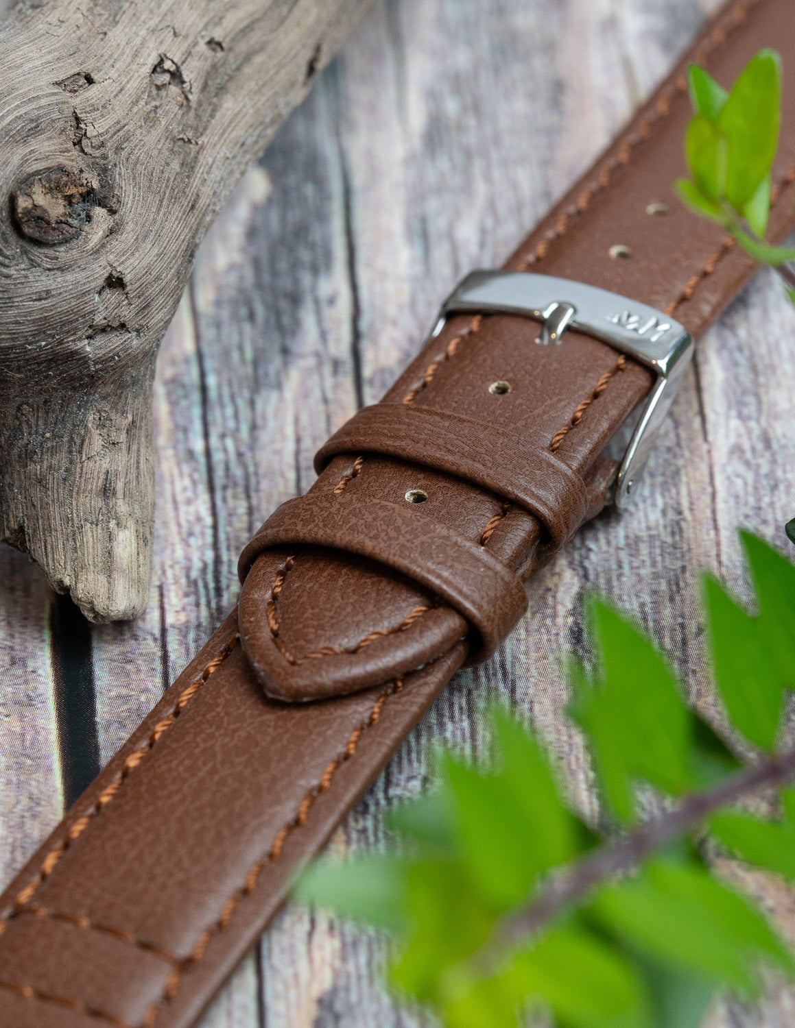 A close up image or a brown faux leather vegan watch strap.