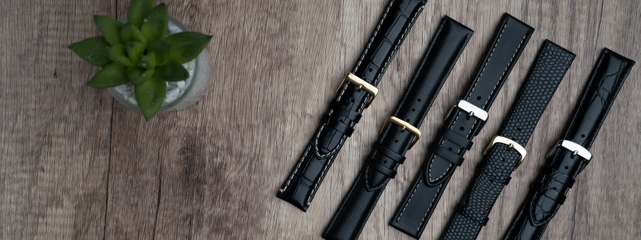 A landscape image of a selection of 5 black watch straps showing different styles and finishes.